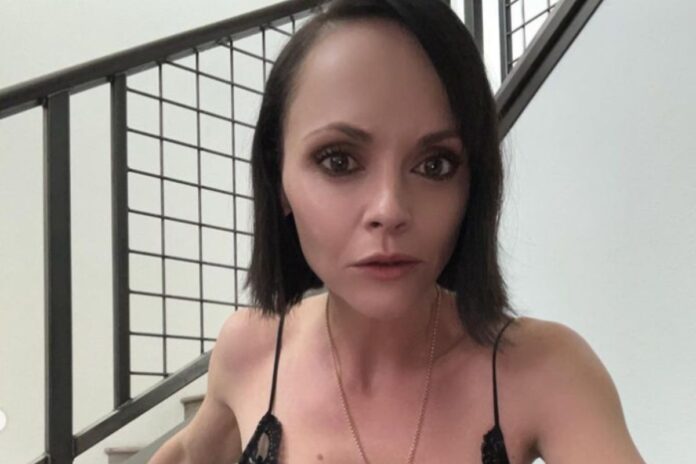 Christina Ricci olhando para a câmera, em foto perto de uma escada